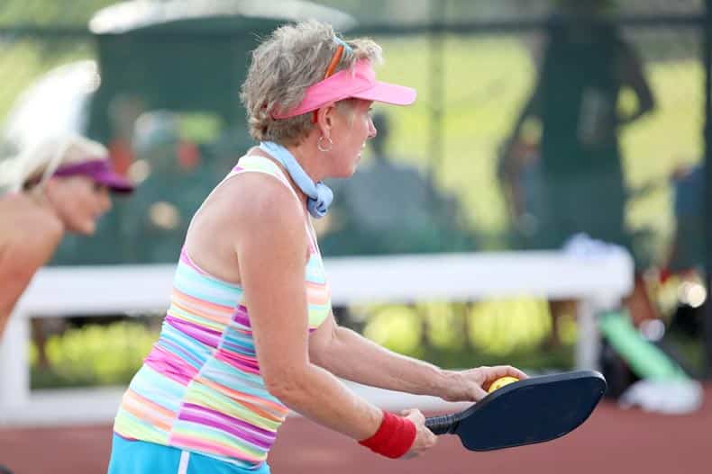 A woman playing pickleball in her 55+ community.