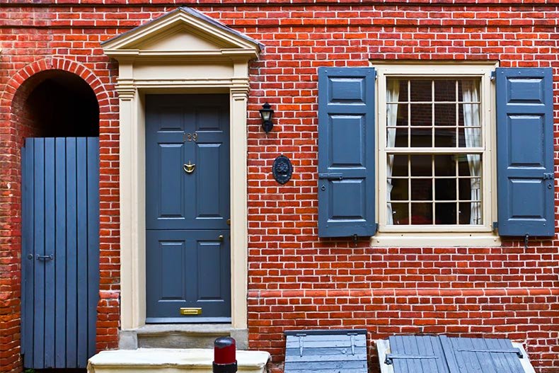 Red brick townhouse with blue shutters, door and gate.