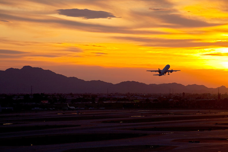 Airplane taking off from Phoenix Sky Harbor International airport at sunset.