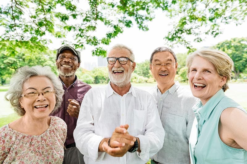 A smiling group of seniors pose for a photo at a 55+ community.