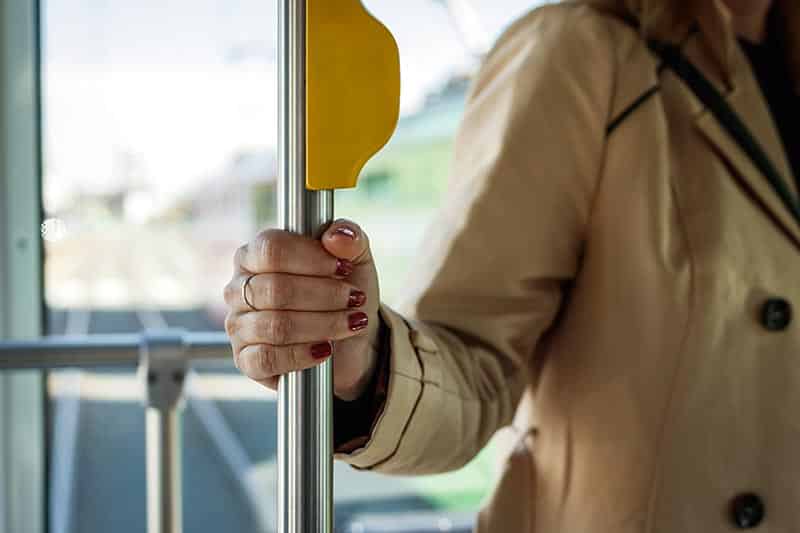 Woman holding a pole on a community transit bus in her 55+ community.