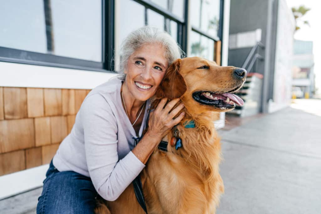 An older woman hugs her dog while living in a 55+ community.