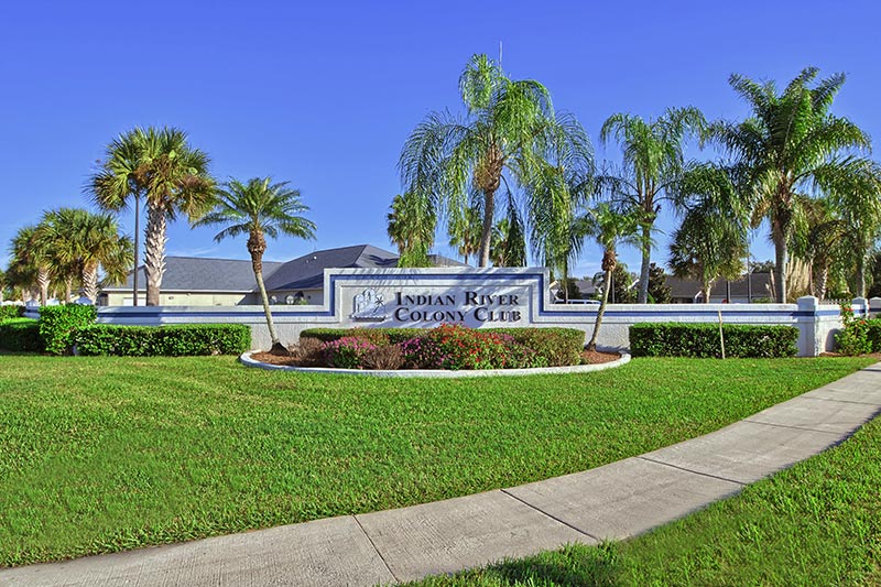 Palm trees surrounding the sign at the entrance of Indian River Colony Club, a 55+ community in Melbourne, Florida