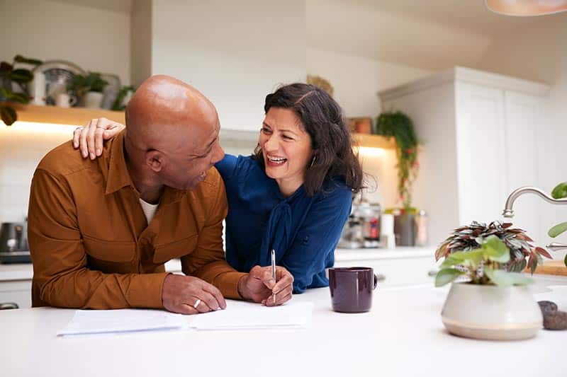 An older couple sit on their couch to discuss financing options for their new home in a 55+ community.