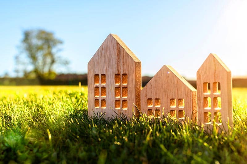 Tiny wooden houses in a grassy field at sunset.