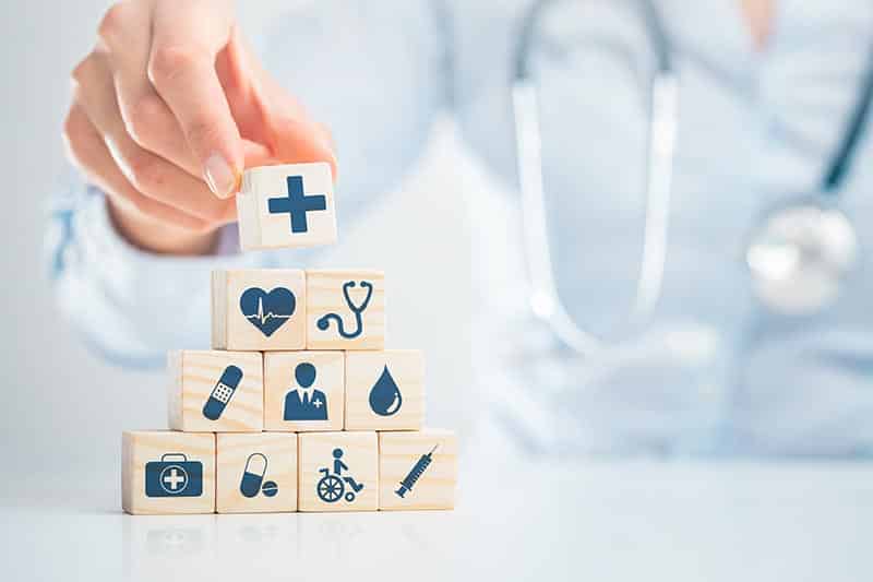 Blocks showing different aspects of healthcare with medical professional in background.