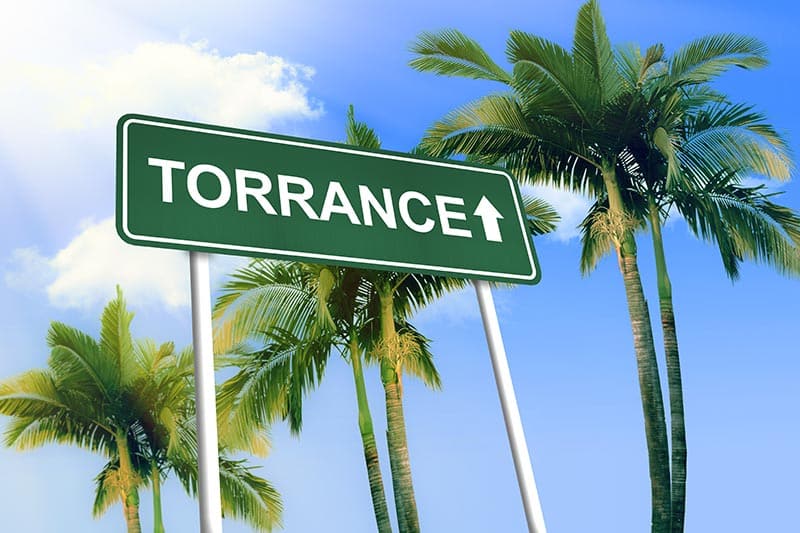 Green Torrance sign with blue skies and palm trees in the background.