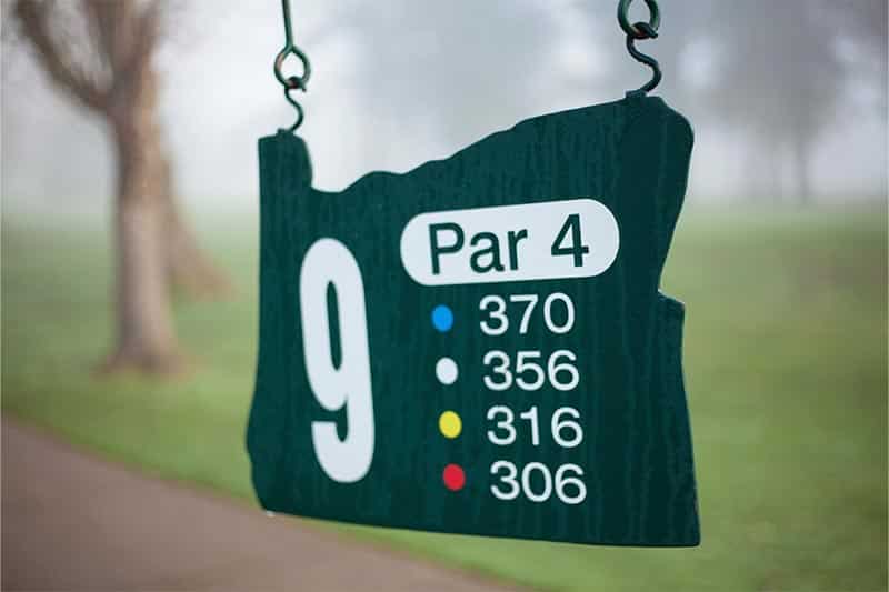 Green sign for hole 9 par 4 at golf course.