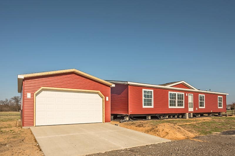 Brick red manufactured home with a bright sky in the background.