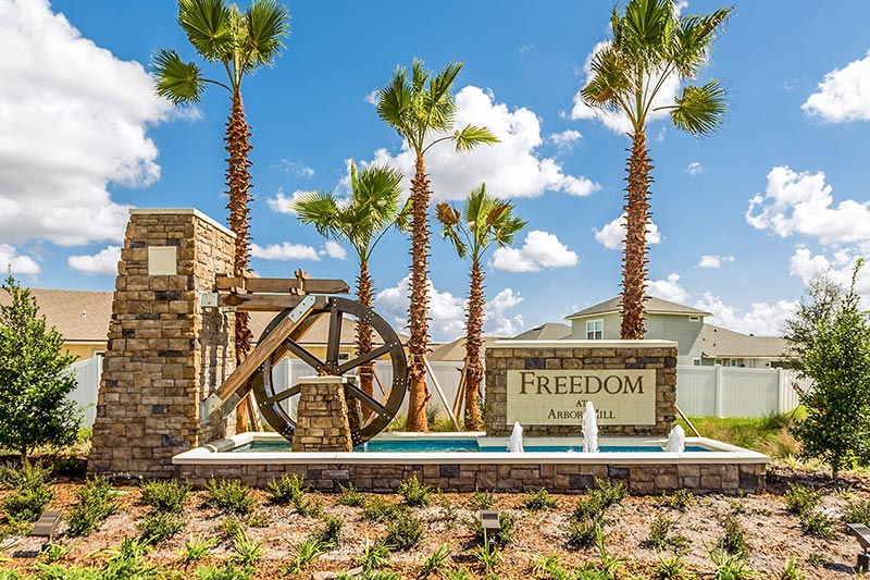 Palm trees behind a water feature at the entrance of Freedom at Arbor Mill in Jacksonville, Florida.