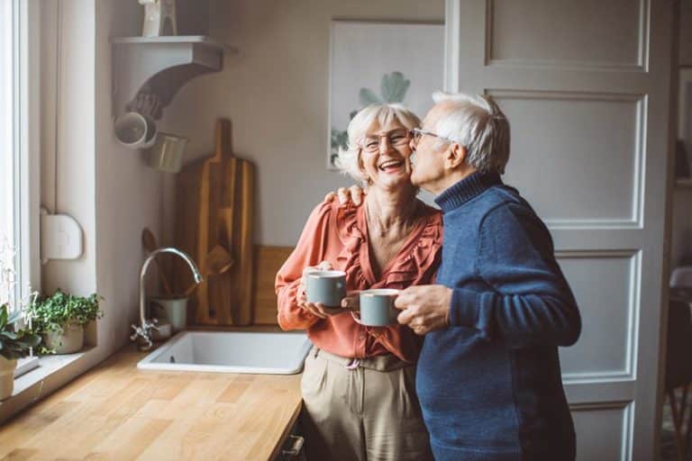 A senior couple enjoys coffee in the kitchen of their home in a Del Webb community.