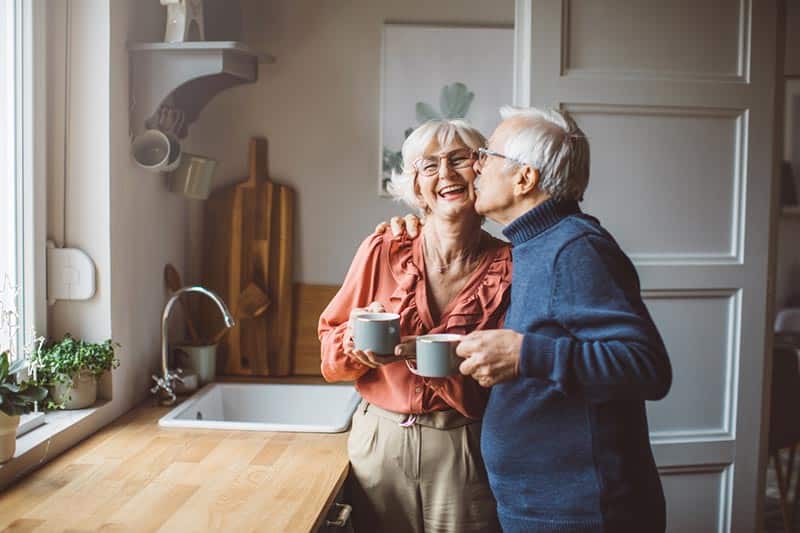 A senior couple enjoys coffee in the kitchen of their home in a Del Webb community.