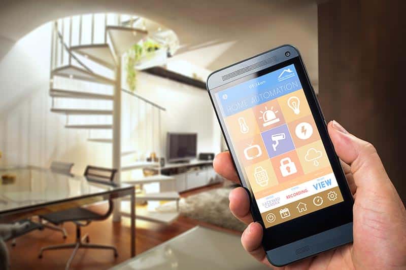 Hand holding phone showing home automation app.