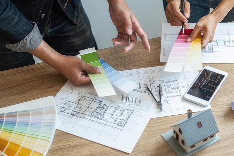 Interior decorators looking at blueprints and paint sample cards.