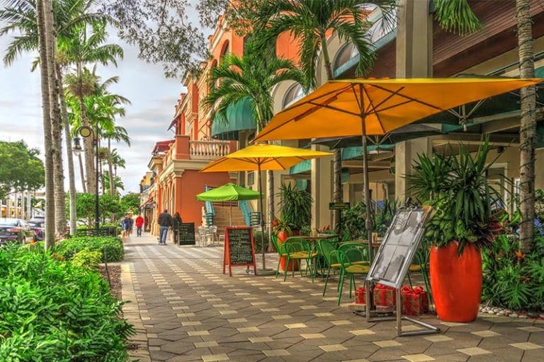 Looking down the sidewalk on a Naples street with shops and restaurants.