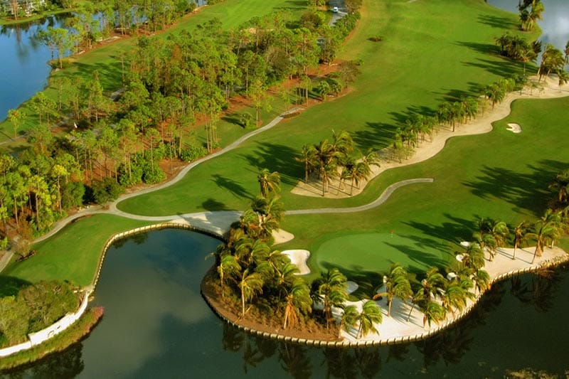 Overhead view of golf course with lake, palm trees and sand traps.