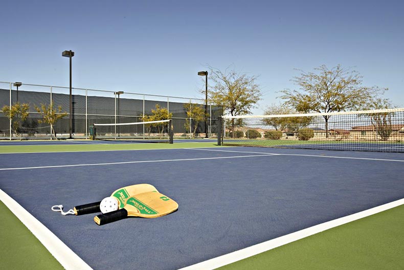 Pickleball paddles and a ball on a court at Del Webb at Rancho Del Lago in Vail, Arizona.