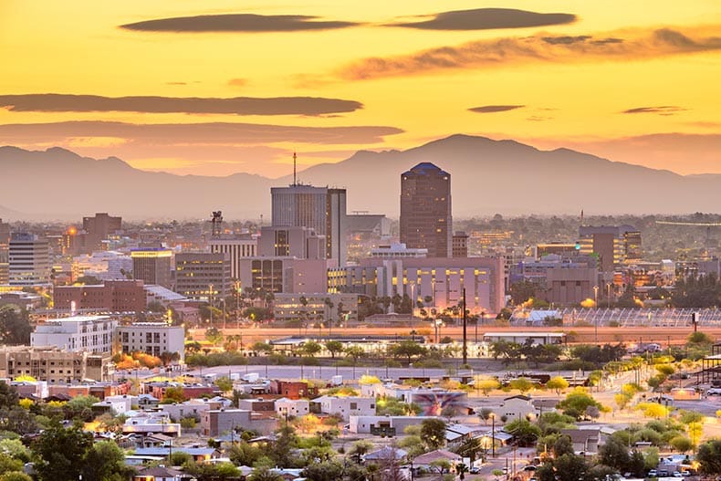 The downtown city skyline of Tucson, Arizona with mountains at twilight.
