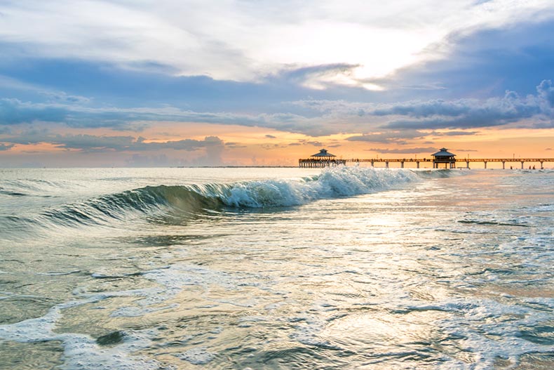 Waves on the beach with a pier in the distance at Estero Island in Florida.