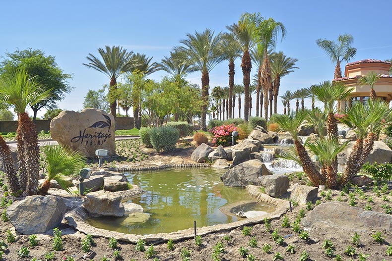 Palm trees and a water feature beside the entrance sign for Heritage Palms in Fort Myers, Florida.