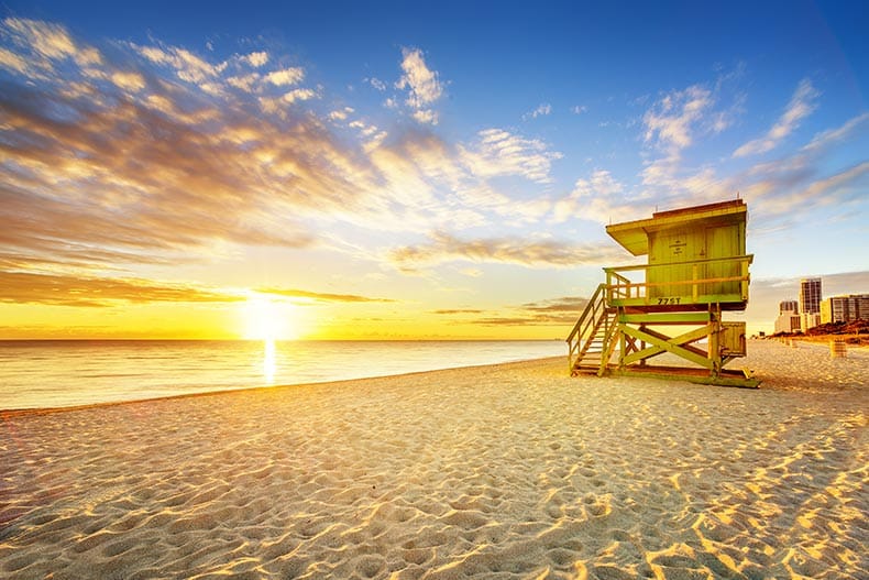 Sunrise over a lifeguard tower and coastline at Miami South Beach.