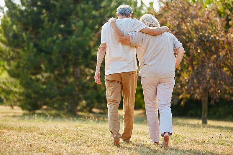 A mature couple walking together in nature in the summer.