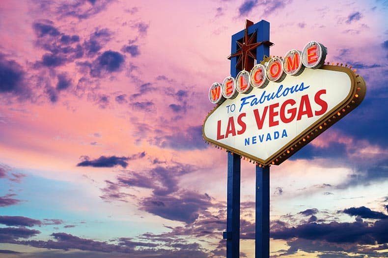 "Welcome To Fabulous Las Vegas Nevada" neon sign set against a sunset sky.