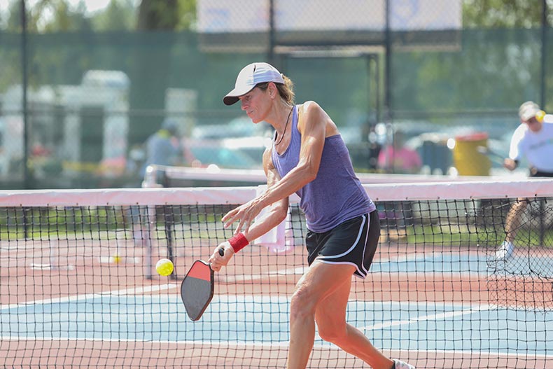 A woman hits a pickleball shot on the court in her 55+ community.