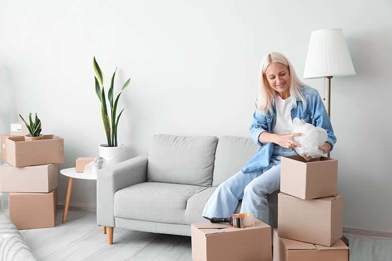 A 55+ woman packing things in a living room on moving day.