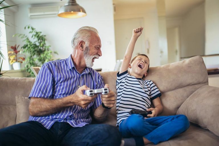 An older adult plays one of the best video games with a young boy.