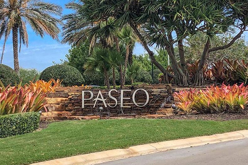 Tropical greenery surrounding the community sign for Paseo, a 55+ community on Florida's Gulf Coast.