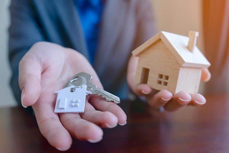 Real estate agent holding house model and keys.