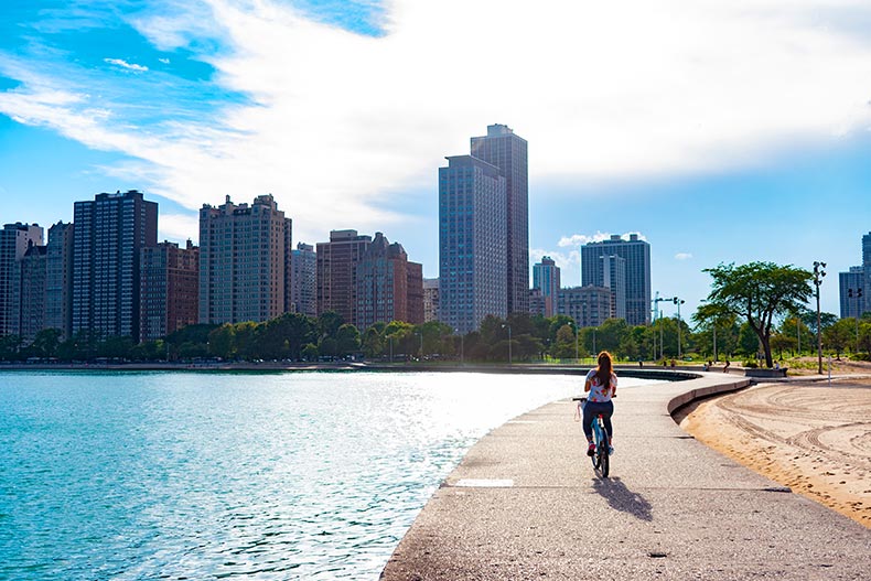 A woman riding a bike along Lake Michigan towards the sun in Chicago, Illinois.