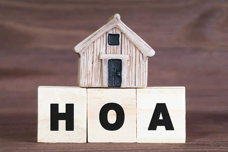 HOA made from wooden letter blocks with a miniature house on top.