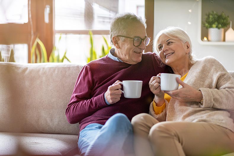 A happy elderly couple relaxing together on the sofa at home in a 55+ community.