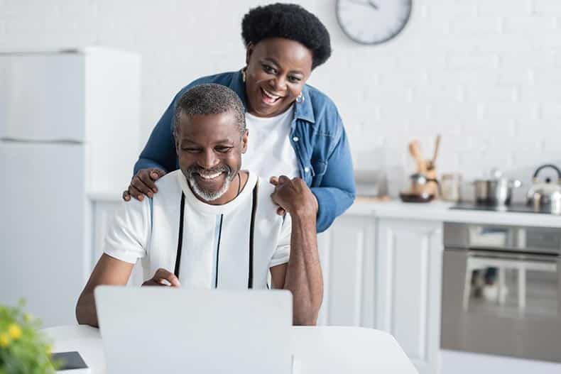 A happy mature couple looking at a laptop at home.