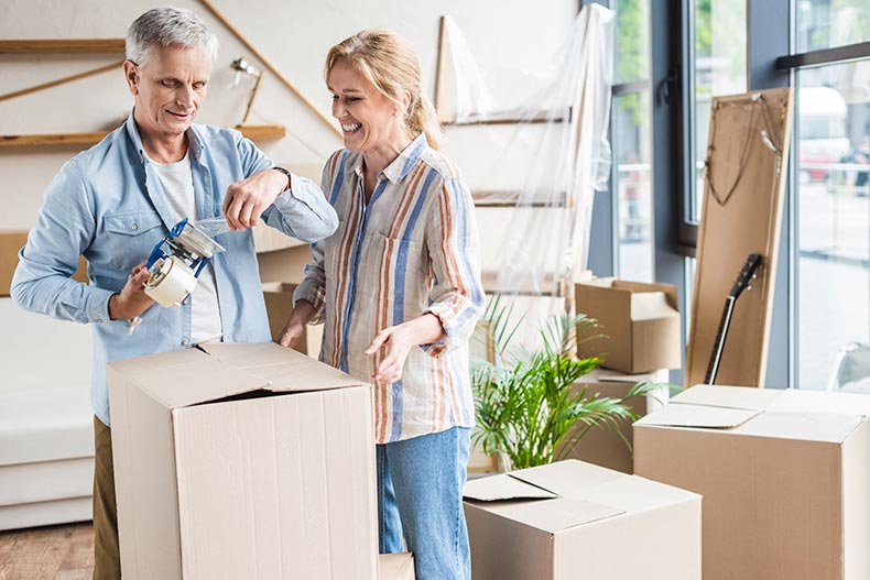 A happy senior couple packing cardboard boxes during relocation.