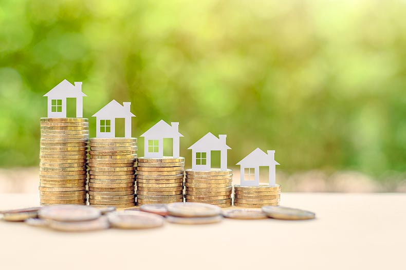 Small houses on stacks of coins with a green background.