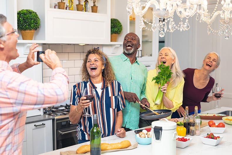 Laughing friends cooking food together at home.