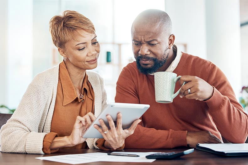 A mature couple with a digital tablet looking over their HOA fees.