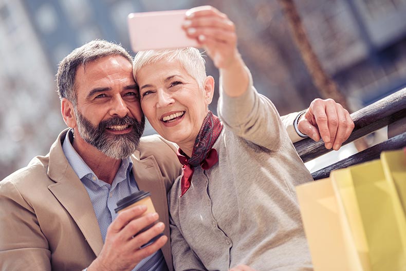 A mature couple with shopping bags taking a selfie in the city.