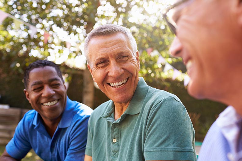 Mature male friends socializing outdoors in their 55+ community.