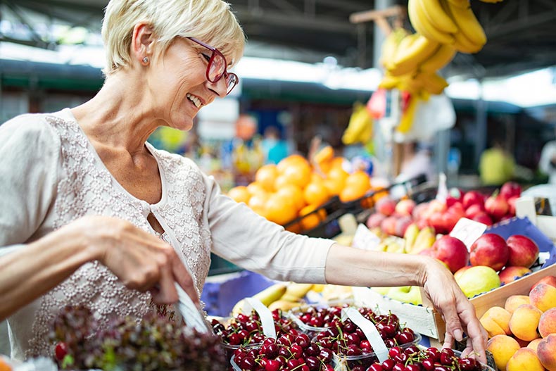 A mature woman at a marketplace buying fruit near her 55+ community.