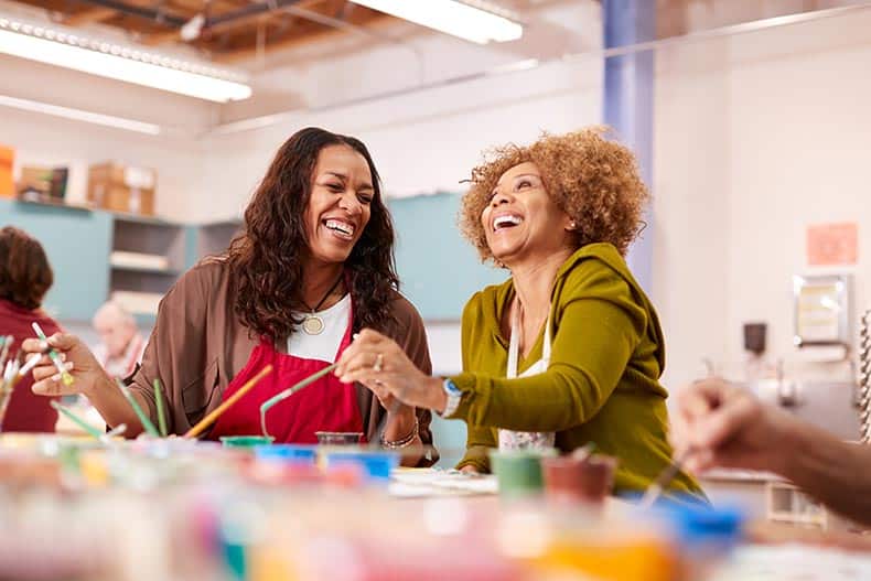 Two mature women attending an art class at the recreation center in their 55+ community.