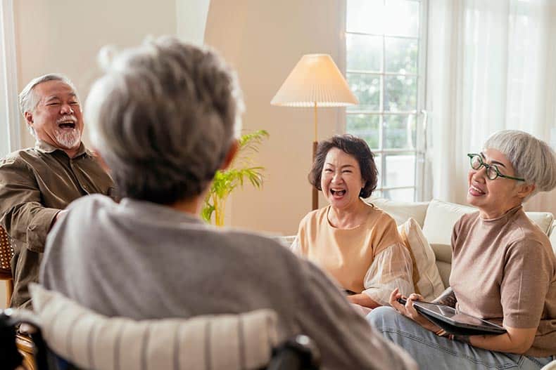 Retired friends laughing together in a living room in their 55+ community.