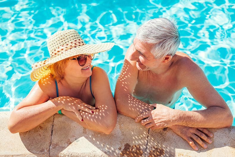 A retired couple relaxing in the resort-style swimming pool in their 55+ community.