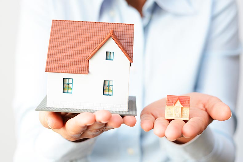 A person holding a large model home and a small model home.