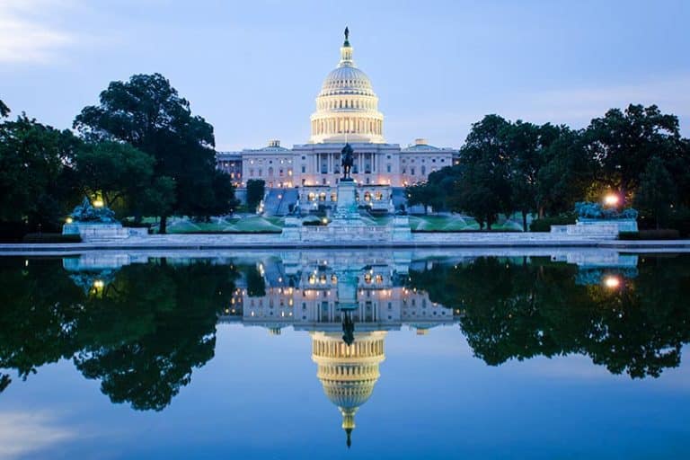 The Capitol Building at sunrise with a reflection on the water in Washington, DC.