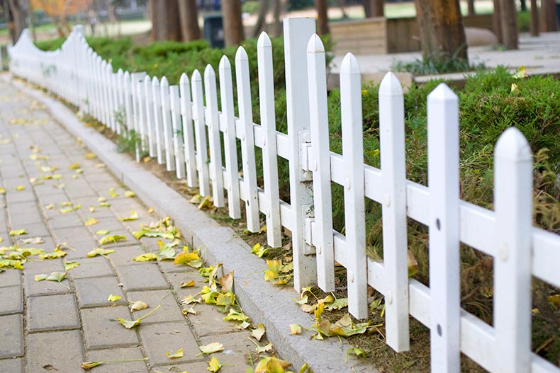 A white fence surrounding a garden.