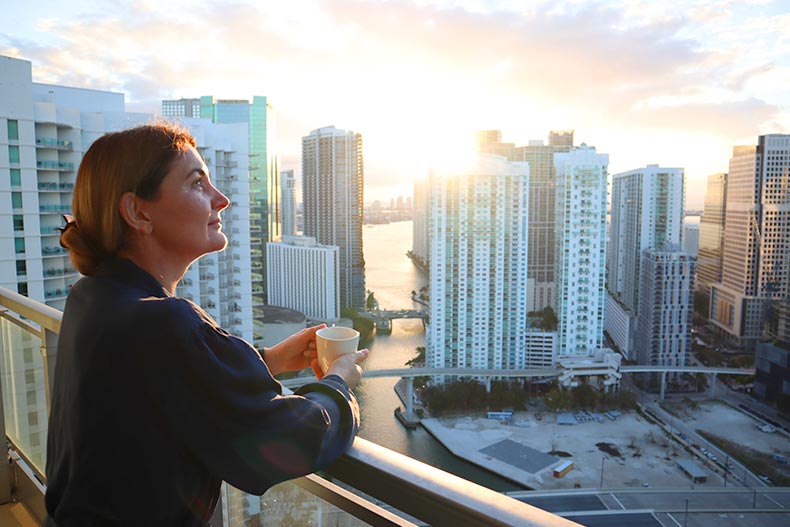 A woman drinking her morning coffee on a balcony overlooking Downtown Miami.